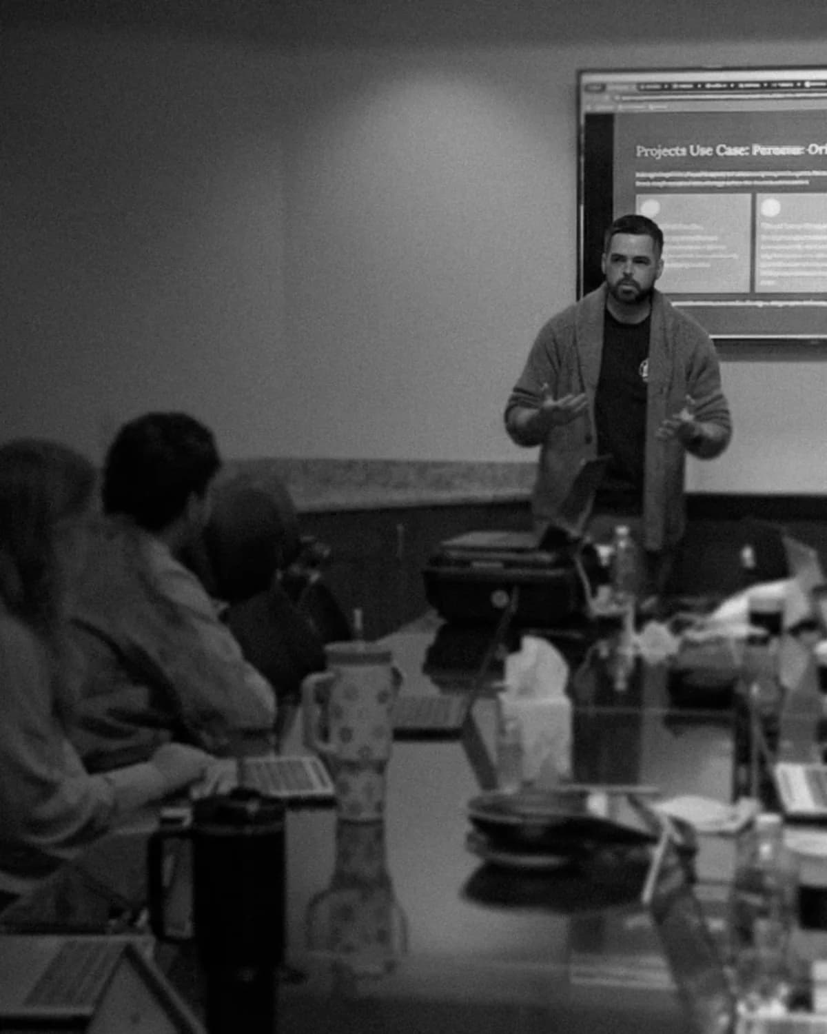 Chris Aumen leads a workshop, standing at a screen while stakeholders around a conference table listen.